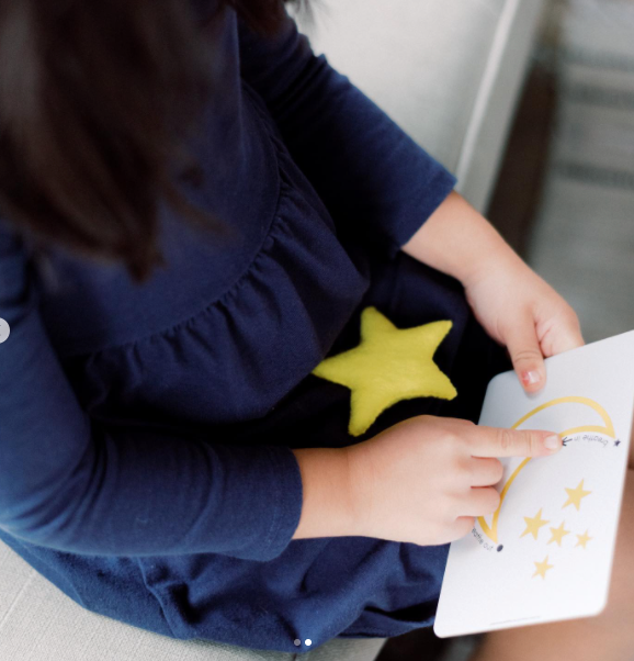 child holding star and tracing breathing card with finger