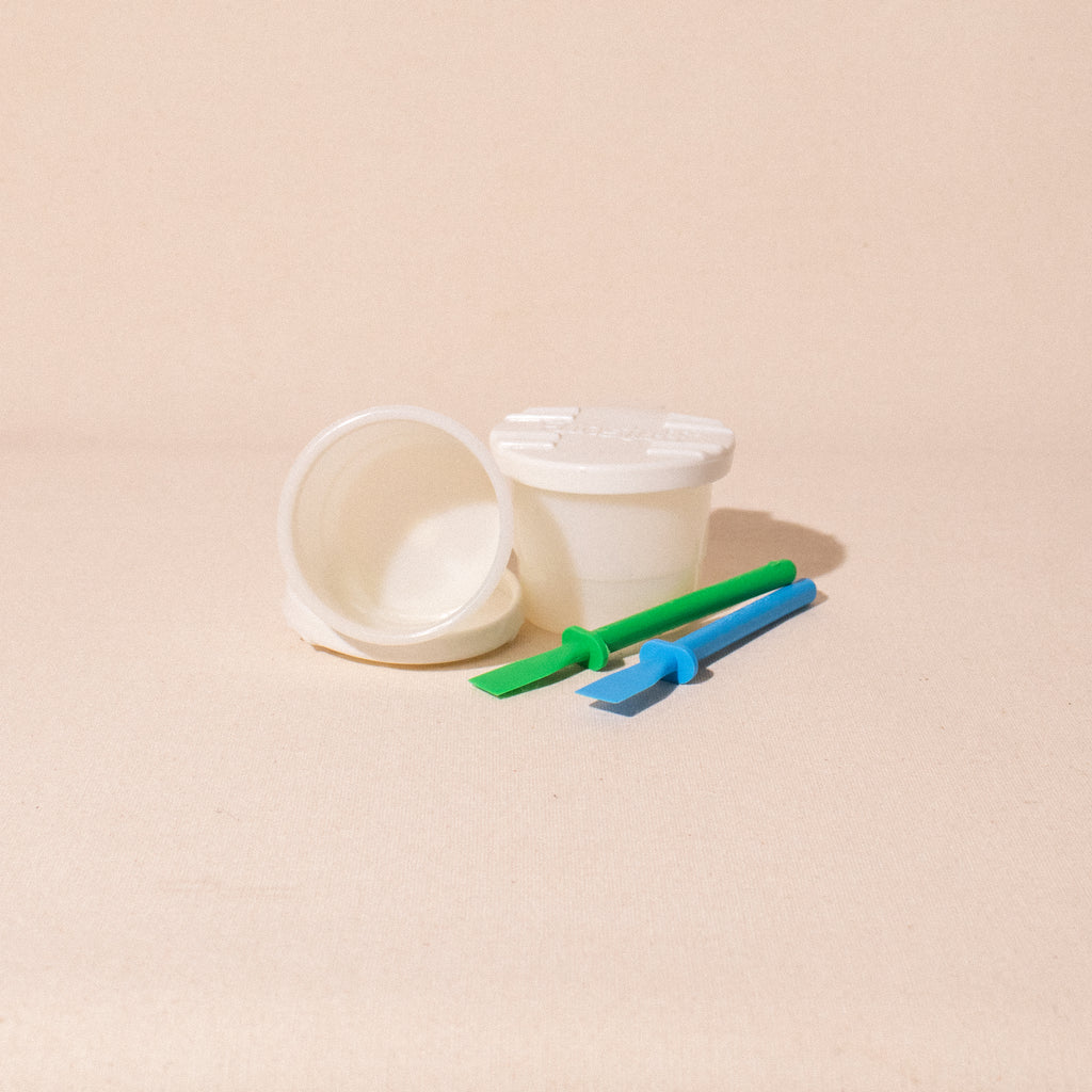white glue pots with lids and two glue spreaders blue and green