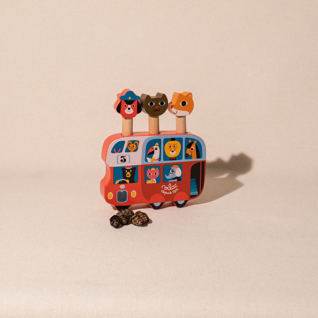 illustrated red wooden bus with fox dog and cat figures popping up on top