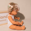 Miniland caucasian baby girl doll showing hearing aid for cochleal implant