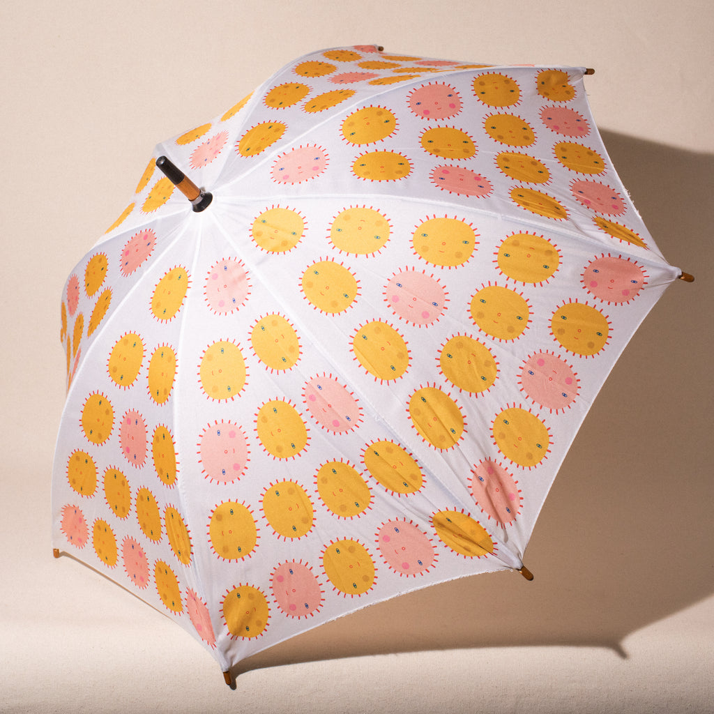 open child's umbrella with pink and yellow suns with faces