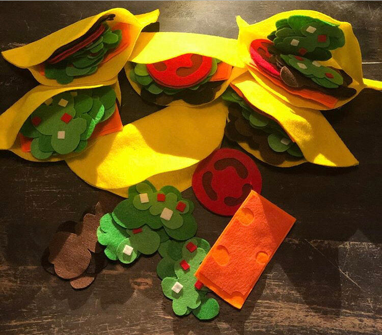 multiple sets of felt tacos with shells, tomato, beans, cheese and guacamole